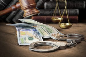 Money, gavel, and handcuffs on the table