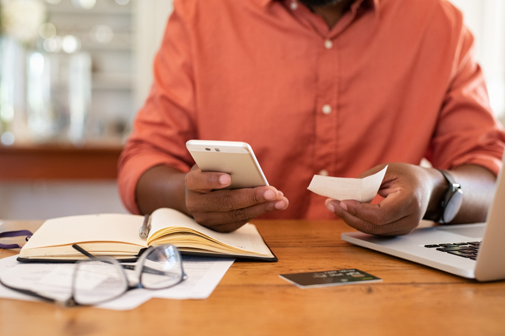 man checking bills and computing with his phone